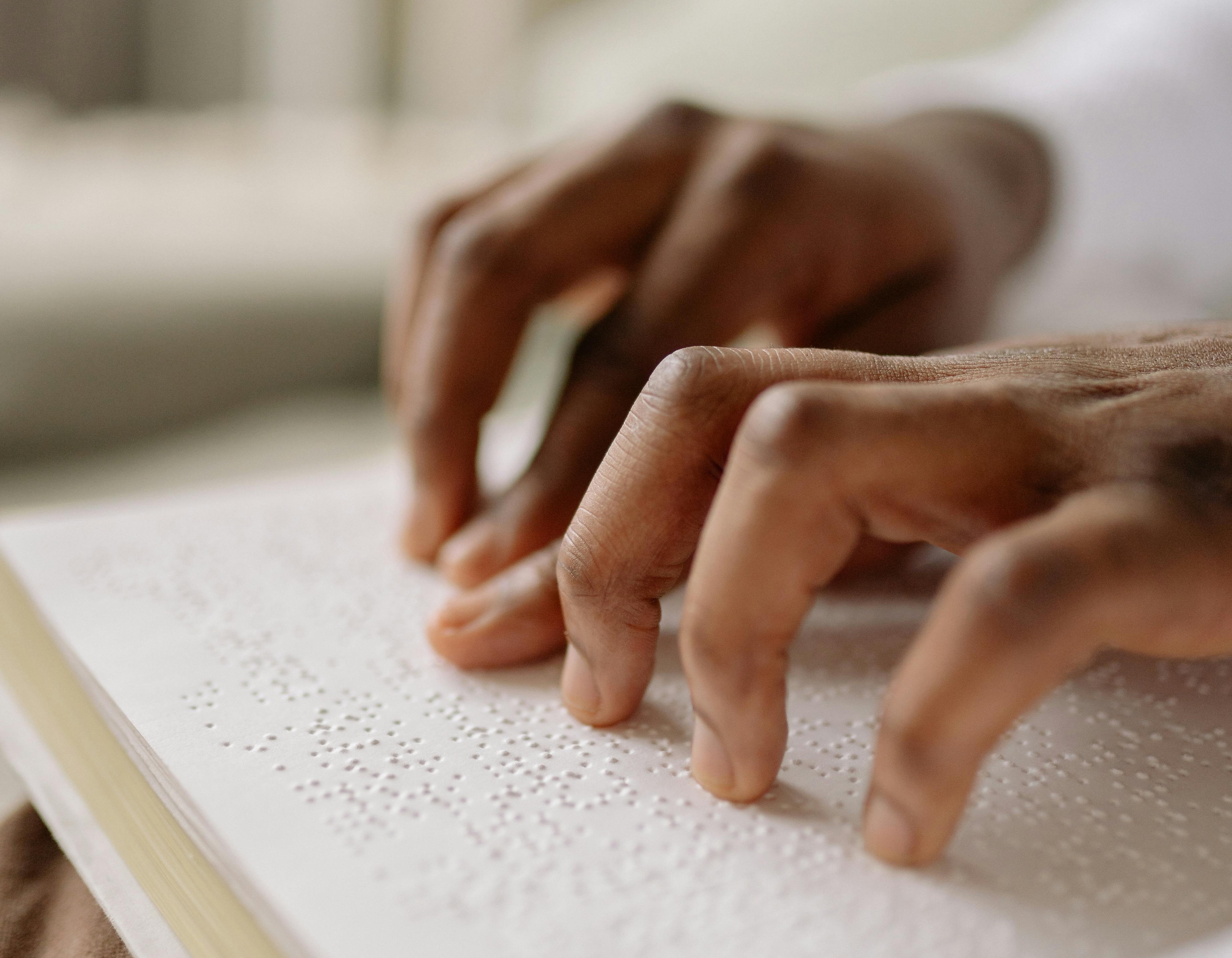 duas mãos fazendo a leitura de um texto em braile